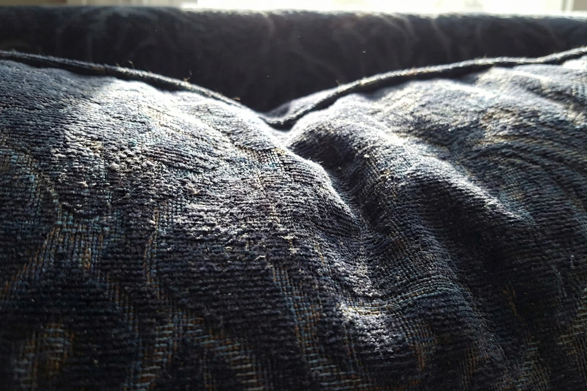 Close up of dark colored patterned cushion fabric in natural home lighting